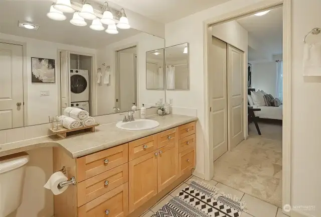 Spacious en-suite primary bathroom with tiled flooring, hanging cabinet mirror and large vanity.
