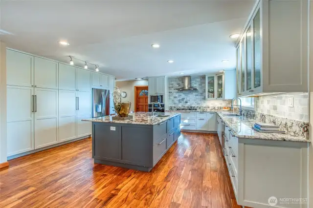 Large granite countertop island anchors the kitchen with tons of cabinet storage to the left and enough counter space for the chef and helpers