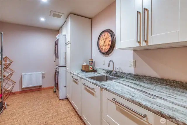 The laundry area has a stacked washer/dry plus plenty of storage space and utility sink