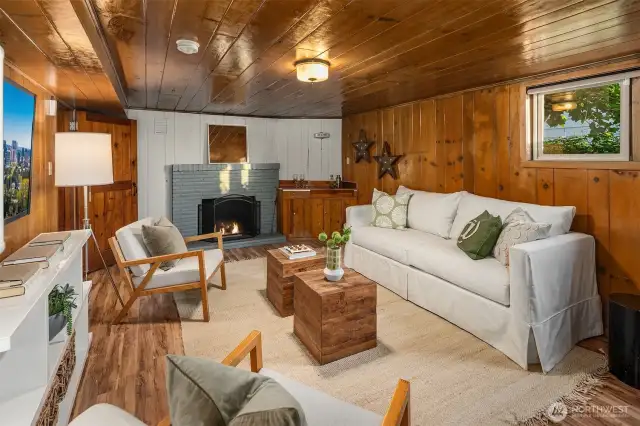 Lower Level living room with wood burning fireplace and classic knotted pine. Note good window light too.