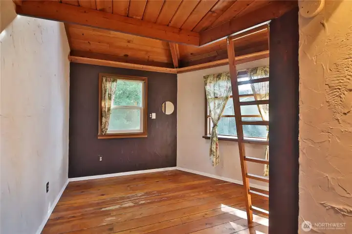 The bedroom on the main level features a lofted area above.