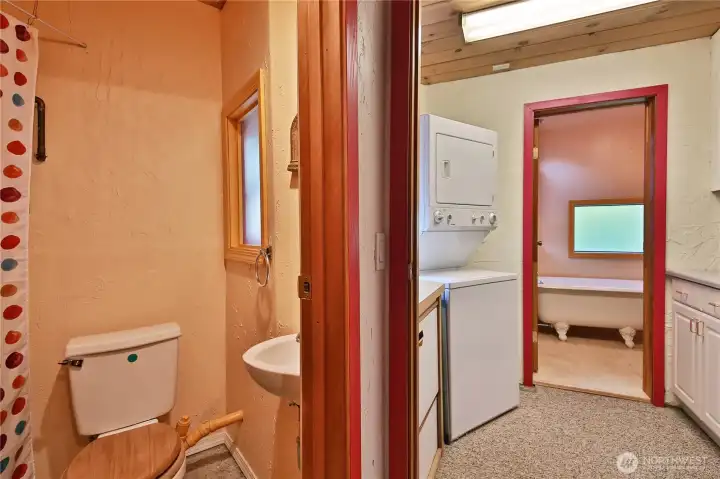 A laundry room with counter space separates the powder room and bath tub.
