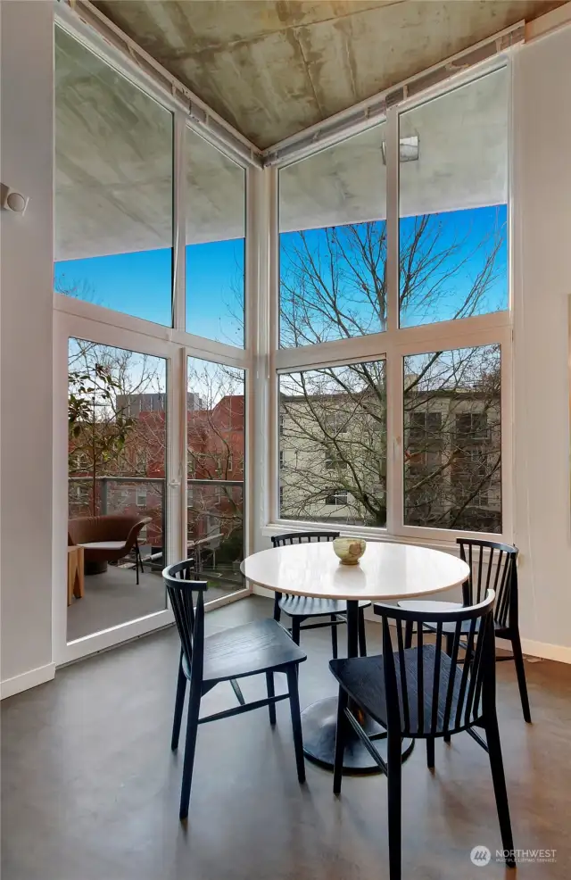 Warm western light pours through the floor-to-ceiling windows, complemented by a private deck with tree-lined and Space Needle views.