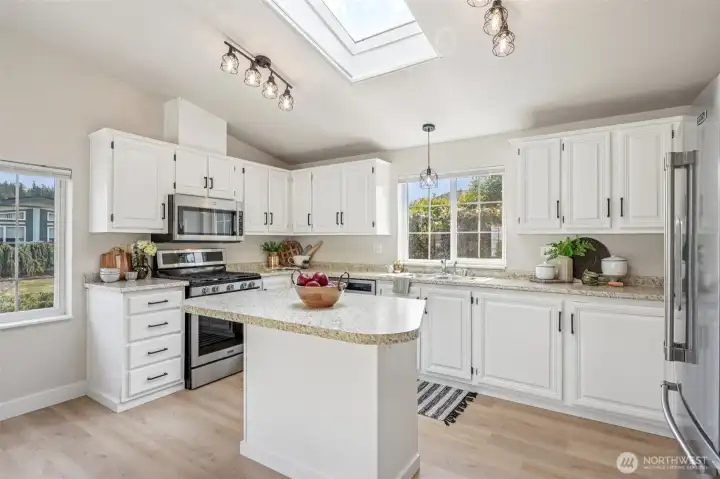 Kitchen with island, stainless steel appliances, and skylight.