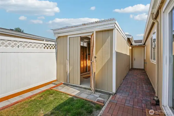 The side view of the house shows a brick hallway with two sheds on the left. The door at the back leads to the garage.