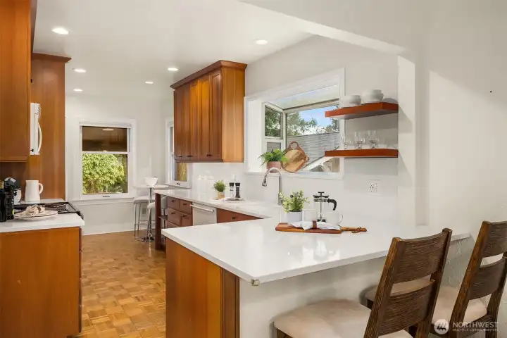 Kitchen featuring custom cherry cabinetry, quartz counters & a versatile eating nook that leads to the backyard & spacious deck.