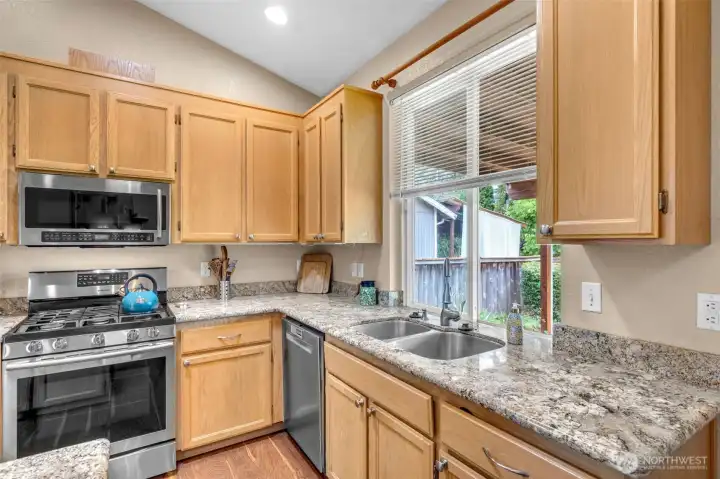 Spacious kitchen offers generous counter space, extensive maple cabinetry, granite countertops, stainless steel appliances, and an open layout that seamlessly connects to the dining area and outdoor living space.