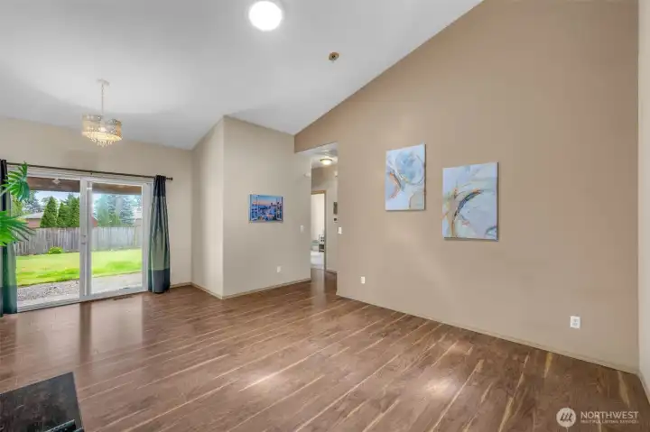 Spacious family room with durable wood-look flooring, recessed lighting, and sliding glass doors that open to the covered patio and fully fenced backyard—ideal for relaxing or entertaining.