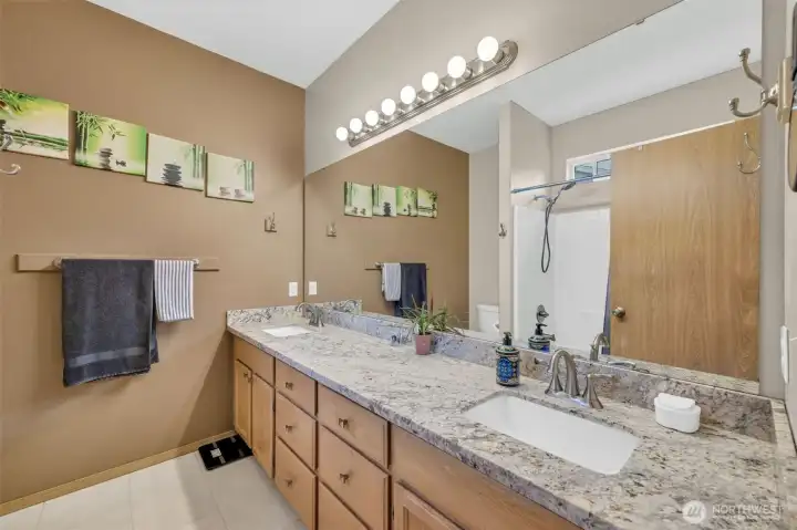 Spacious primary bath with granite countertops, dual undermount sinks, expansive vanity, abundant storage, and plenty of room to start and end your day in comfort.