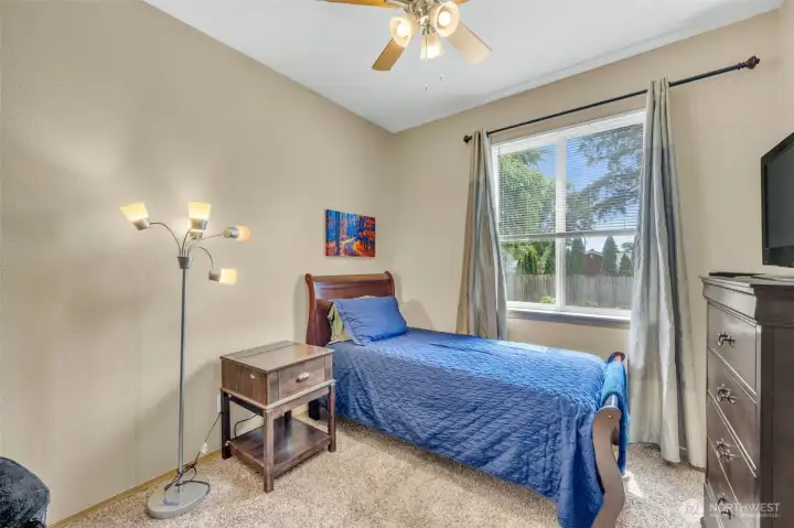 Bedroom #2 with plush carpeting, ceiling fan, generous closet space, and a large window that fills the room with natural light.