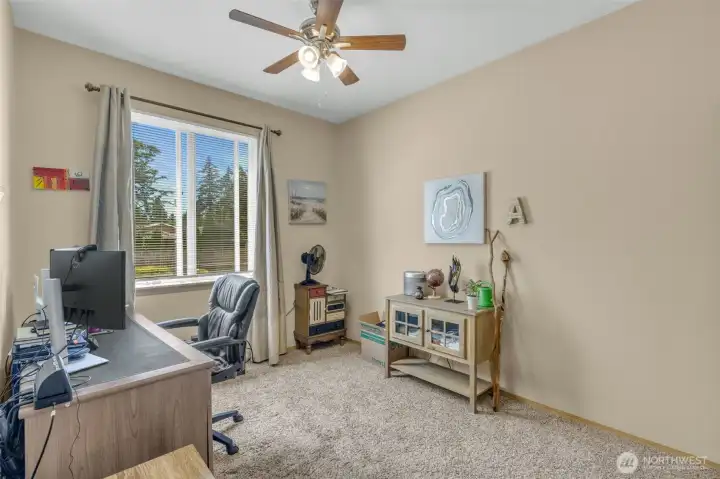 Bedroom #3 with plush carpeting, ceiling fan, and large window offering abundant natural light. Ideal as a guest room, home office, or hobby space.