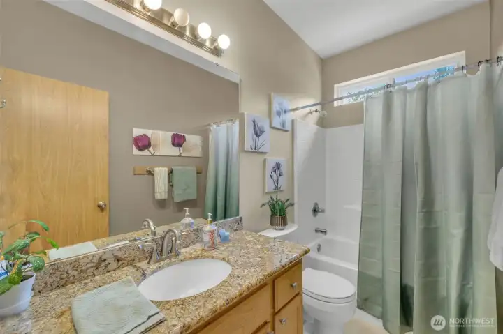 Well-appointed full bathroom featuring granite countertops, an undermount sink, and a tub/shower combination with a transom window that provides natural light while maintaining privacy.