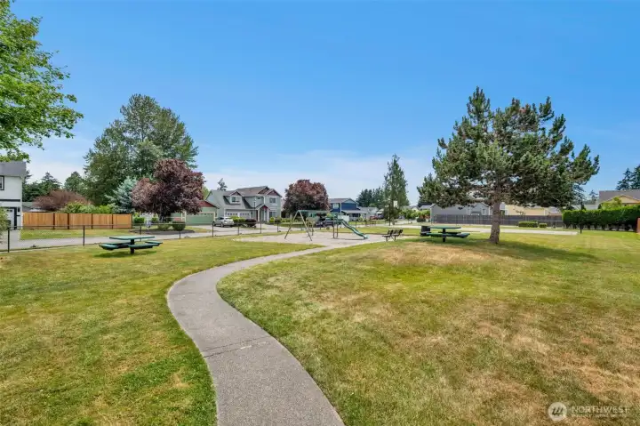 Residents enjoy a neighborhood park complete with playground, picnic tables, open green space, and sports court.