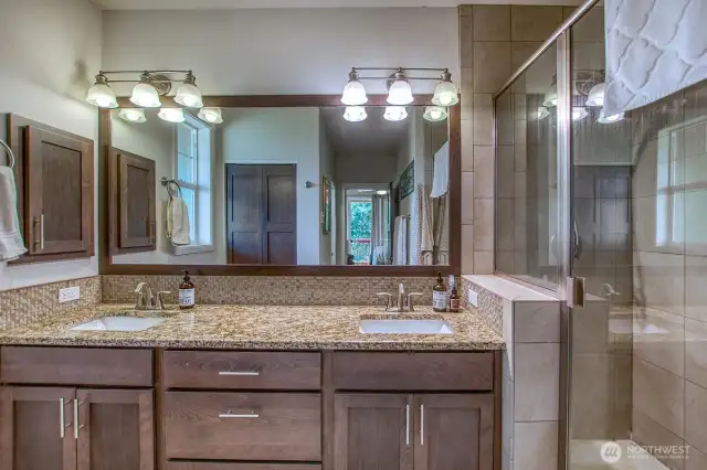 Ensuite primary bath with double vanity and walk in tiled shower.