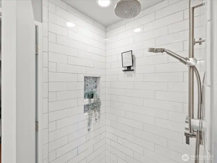 Main level walk in shower with rain shower head and separate handheld shower fixture.
