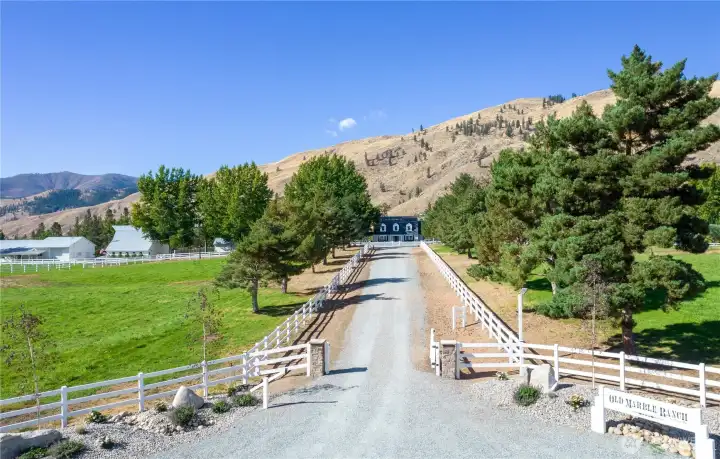 Marble Ranch—a lovingly preserved 1930s farmhouse with classic dormers, covered porch, updated systems, and timeless curb appeal framed by mature trees and manicured lawn.