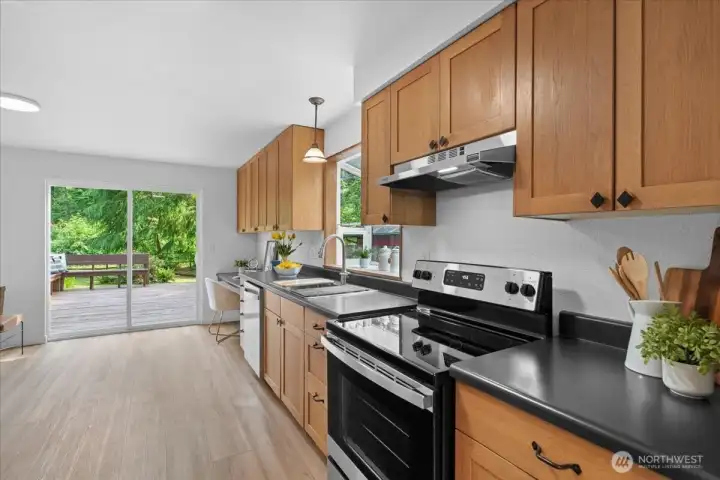 Kitchen – Well-appointed kitchen with extensive counter space, wood cabinetry, stainless steel range, and backyard-facing window.