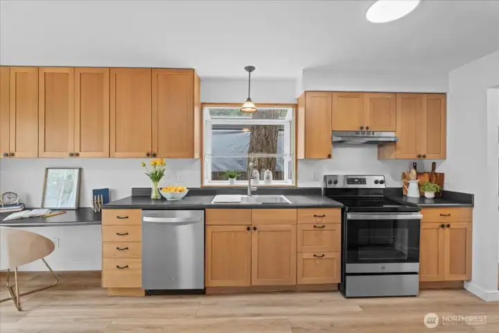 Kitchen – Functional kitchen with extensive counter space, stainless steel appliances, and generous storage. Window above the sink offers views of the surrounding landscape.