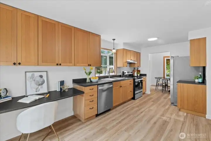 Kitchen – Well-designed kitchen featuring abundant cabinetry, built-in desk area, stainless steel dishwasher, and efficient workspace layout.