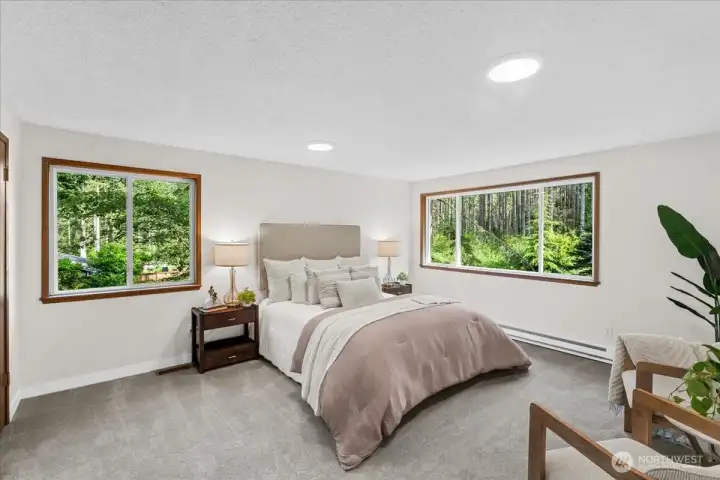 Primary Bedroom – Spacious primary bedroom with fresh carpeting, large windows, and serene views of the surrounding landscape. Generous floor area offers flexibility for furnishings and seating.