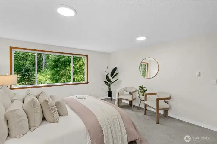 Primary Bedroom – Bright and comfortable bedroom with oversized window, neutral finishes, and peaceful wooded outlook. Ample space creates a relaxing retreat.