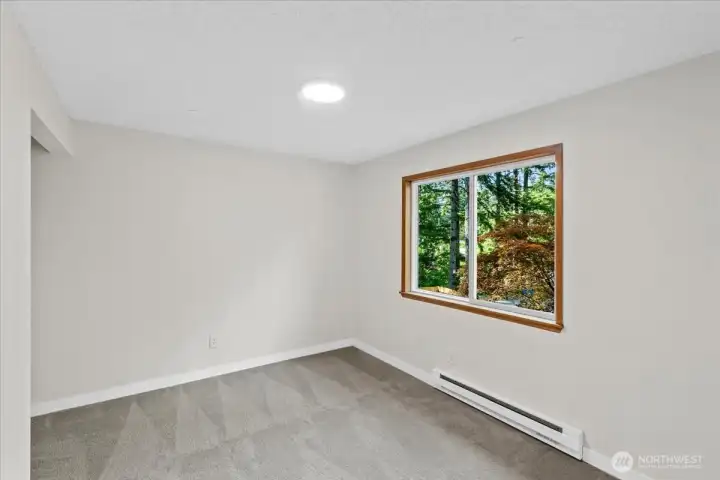 Bedroom – Secondary bedroom featuring new carpeting, generous natural light, and a peaceful outlook through the large window.
