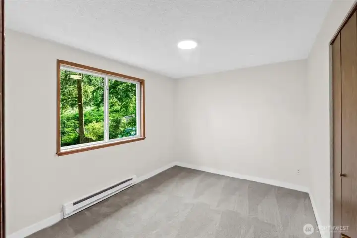 Bedroom – Third comfortable bedroom with fresh carpeting, large window, and views of the surrounding trees. Neutral finishes create a bright and versatile space.
