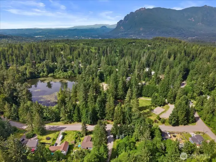 Aerial View – Elevated perspective showcasing the property's forested surroundings, Brewster Lake, and mountain backdrop.