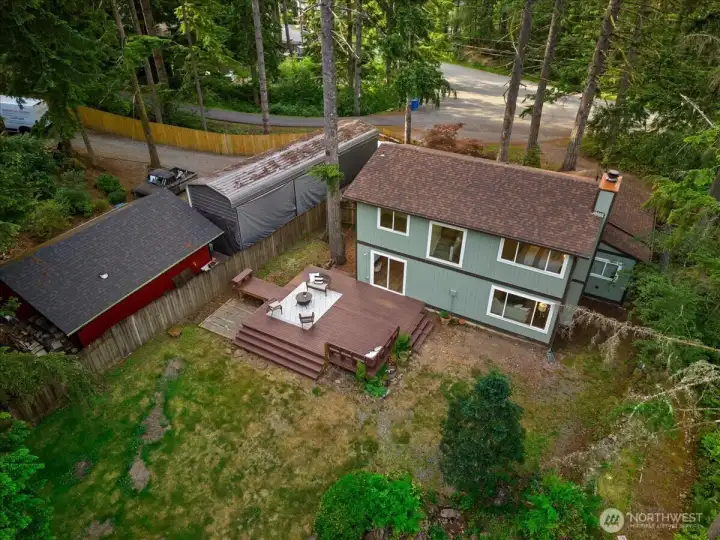 Aerial View – Bird’s-eye view of the home, deck, and backyard, illustrating the property's private setting among mature evergreens.