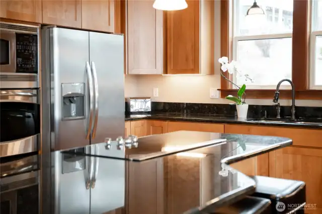 View of kitchen w/ custom wood cabinetry, granite countertops and stainless steel appliances.