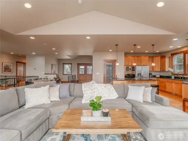 View of living room looking towards kitchen and entryway w/ vaulted ceilings.