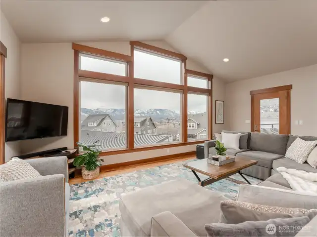 View of living room w/ vaulted ceilings, hardwood floors and oversized windows with uplake views of Lake Chelan.