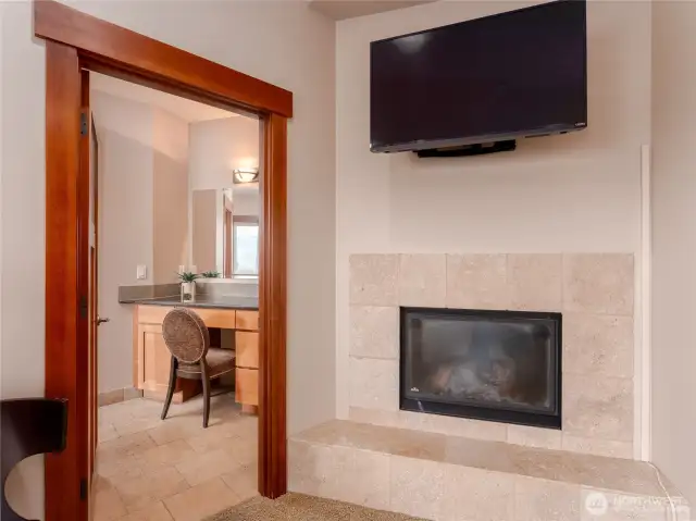 View of the main level Primary Bedroom Suite  fireplace looking towards the spa-like bath w/ vanity area and Jacuzzi tub.