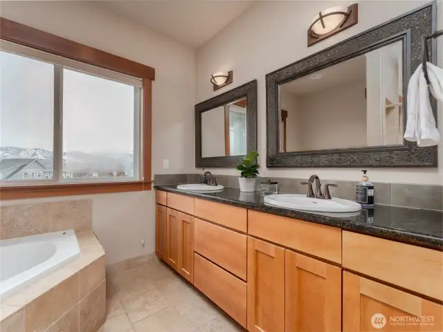 View of the main level Primary Bedroom Bathroom Suite w/ double vanities, granite countertops and a spa-like Jacuzzi tub.