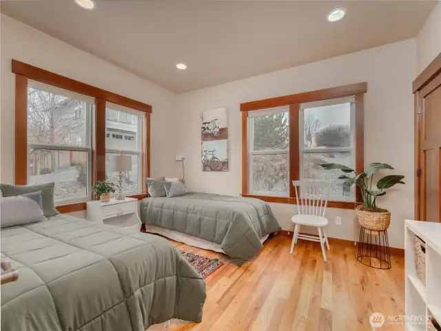View of main level guest bedroom w/ hardwood floors, oversized windows and large closet.
