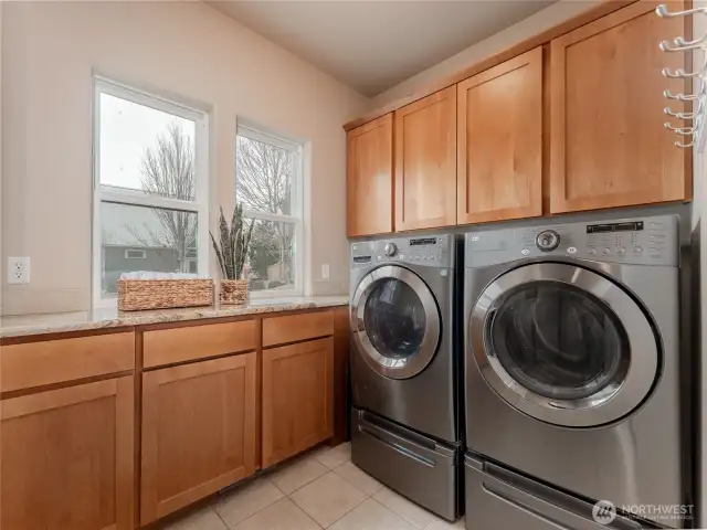 View of main level utility room w/ custom wood cabinetry, high-end appliances and tile floors.