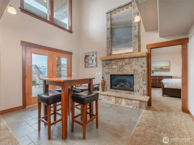 View of lower level area w/ dining area, fireplace, water feature and French doors leading to the outdoor living area w/ dining, lounge and BBQ areas looking towards the 2nd Primary Bedroom Suite.