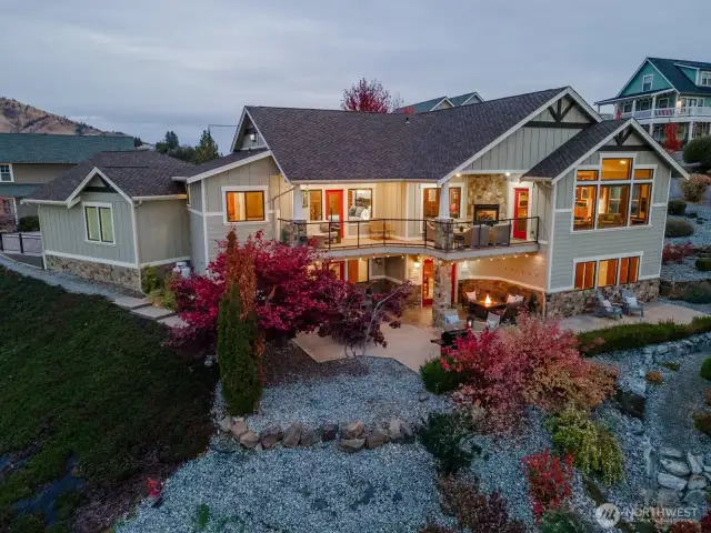 Aerial twilight view of the 5bd/4th 3,441sf home w/ upper level Lake Chelan view decks and lower level outdoor living area w/ dining, lounge and BBQ area.
