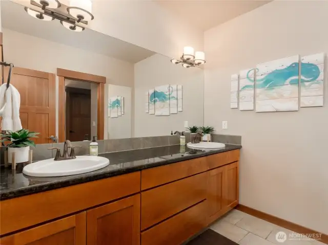 View of lower level bathroom suite w/ double vanities, linen closet and European tiled shower.
