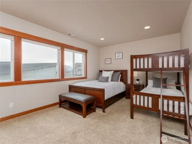 View of lower level bedroom 3 w/ oversized windows, double closets and a queen bed plus full size bunk beds.