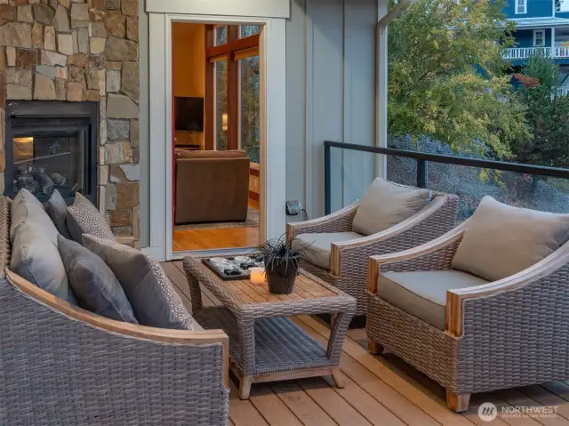 View of upper level lake view deck lounge area w/ double sided store fireplace.