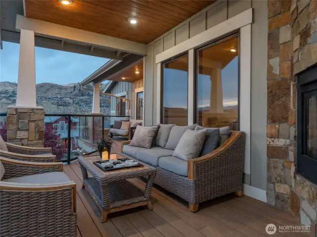 Main level covered lake view deck lounge area w/ double sided stone fireplace.