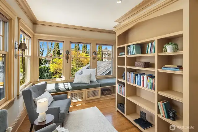 Upper level library/office/reading room with walls of windows and built-in bookcases.