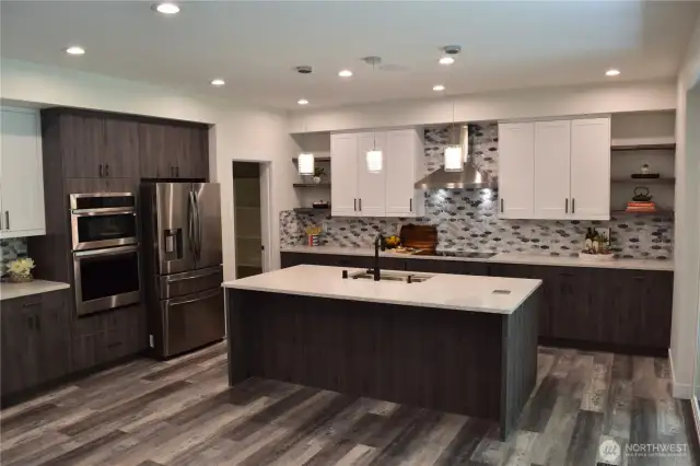 This Gourmet Kitchen Features Luxurious Belmont Cabinets with Soft Close Doors and Drawers. Gorgeous Slab Quartz Countertops. Notice the Elegant Tiled Backsplash. Cooktop is currently electric but is plumbed for a Gas Cooktop too.