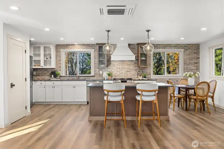 Custom kitchen that beautifully coordinates with main house featuring same honed granite countertops, brick backsplash, LG stainless steel appliance package and pendent lighting.