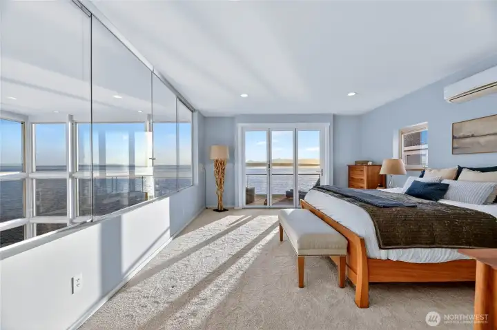 The primary suite features sliding glass windows overlooking the living space below, with a NanaWall opening to a private balcony.