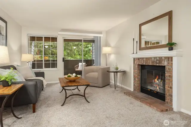 Living room with fireplace, large window and sliding door opening to covered balcony (buyer to verify functionality of fireplace - fire added to photos for appeal).