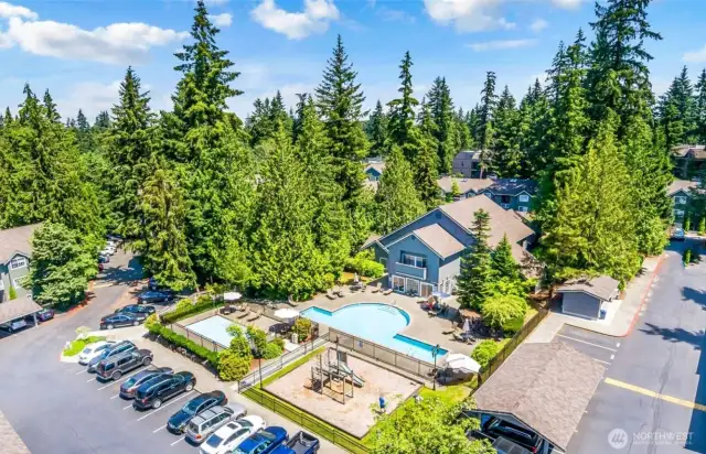 Aerial view of complex featuring clubhouse, two pools, and playground.