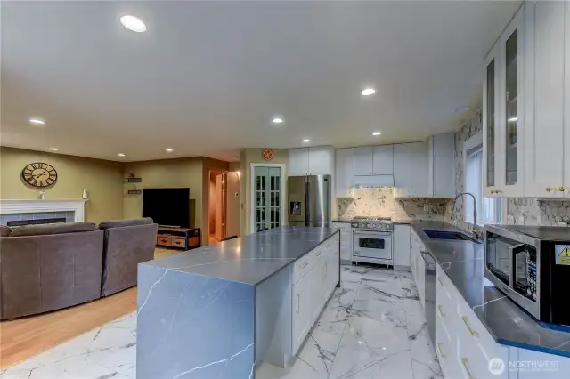 This beautifully updated kitchen 2021 is the heart of the home, featuring striking hexagonal mosaic backsplash, elegant quartz countertops, and a sleek black waterfall island.