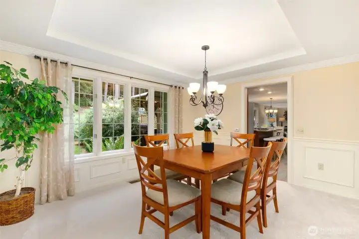 Elegant formal  dining with Coffered ceilings and Wainscot looking out to the lush property.